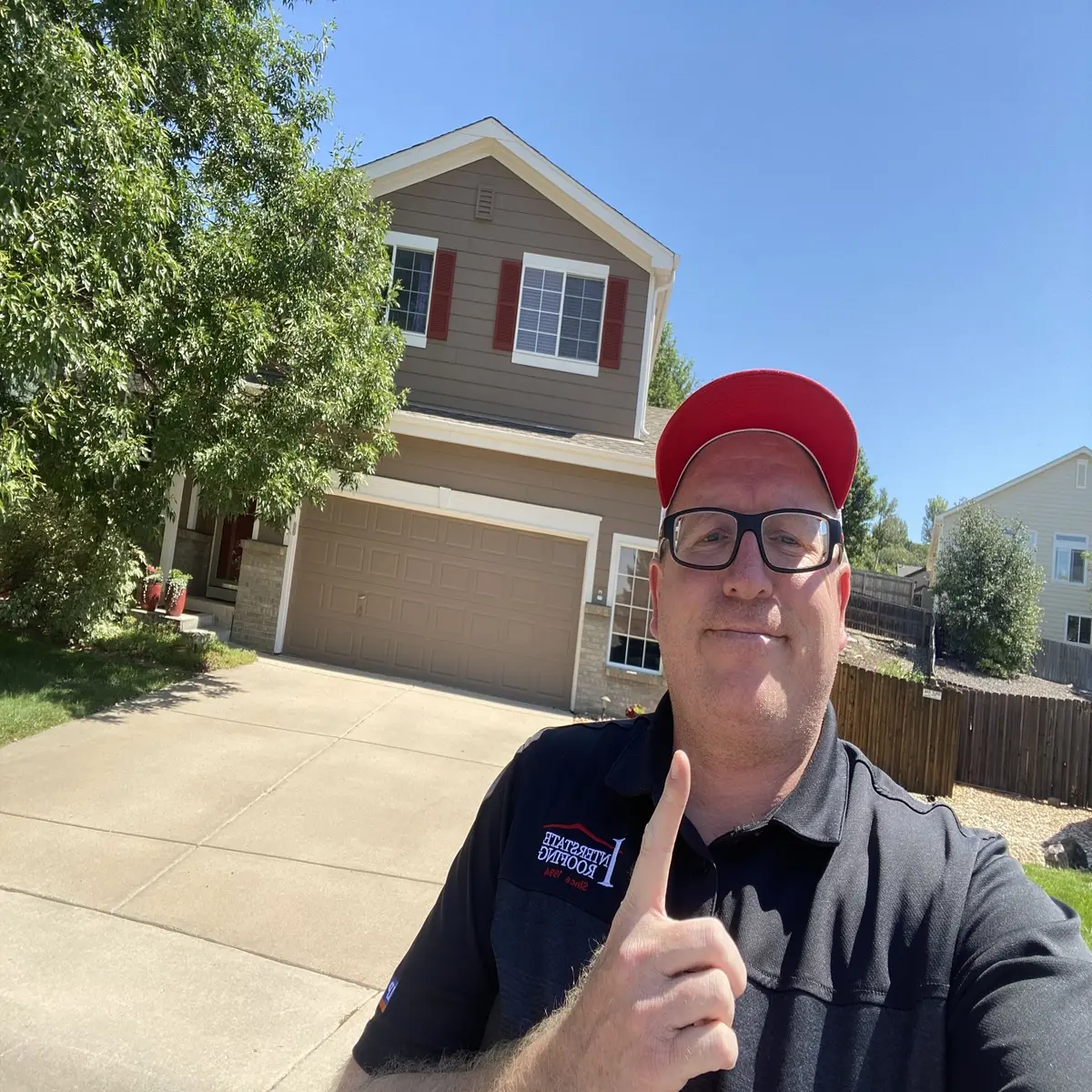 Matt from Spencer Roofing giving thumbs up in front of residential home